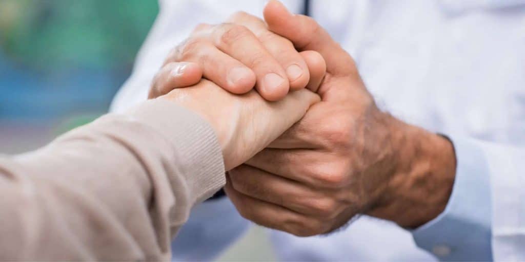 A doctor holding an elderly persons hand